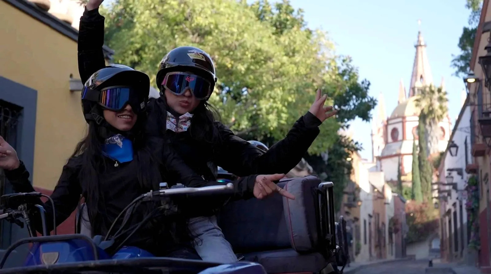 Happy riders enjoying guided UTV Tours through historic city street Cheerful tourists wearing helmets and goggles posing on an all-terrain vehicle near a church during UTV Tours.